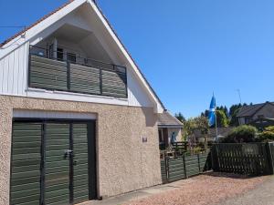 a house with green garage doors and a balcony at Nest Holiday Home Central Callander, Trossachs Self-catering in Callander