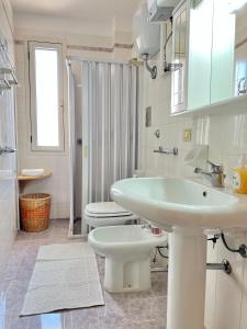 een witte badkamer met een wastafel en een toilet bij Holiday salento in Leuca