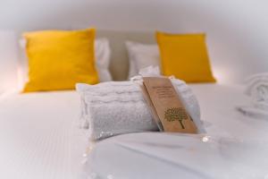 ein Stapel Handtücher auf einem Bett mit zwei gelben Kissen in der Unterkunft Sunny Suite with lake view in Melide