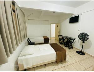 a bedroom with two beds and a table with a fan at Hotel Gran Solar Br in Contagem