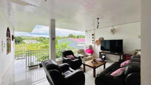 a living room with black leather furniture and a tv at D'Flora Homestay in Labuan Bajo