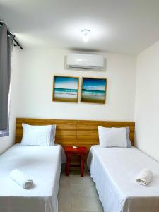 two beds in a room with white sheets at Chaleville Barrinha in Barrinha