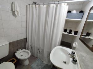 a white bathroom with a toilet and a sink at Departamento céntrico in Tandil