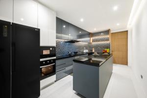 a kitchen with black cabinets and a black counter top at MANDLA VILLAS COLLECTION, White Anda Naiharn in Rawai Beach
