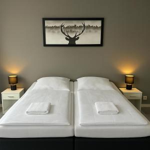 a bedroom with two white beds and a deer picture on the wall at Apartment Gray Z2 in Erfurt