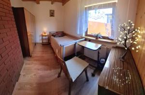 a small room with a bed and a table and a window at Agroturystyka Nad Wisłą in Brzumin +4 photos