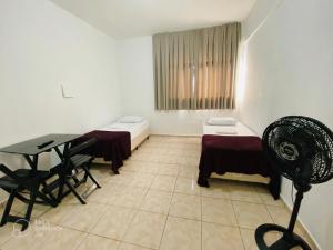 a room with two beds and a table in it at Hotel Gran Solar Br in Contagem