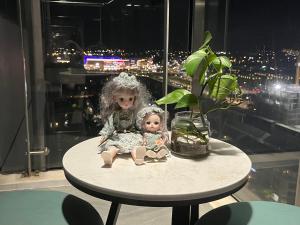 two dolls sitting on a table next to a plant at Joie Apartment Hue in Thôn Văn Dương