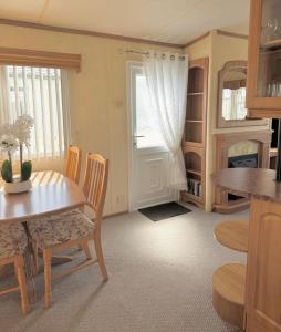a dining room with a table and chairs and a window at 2 bedroom cosy caravan, Sealands in Ingoldmells
