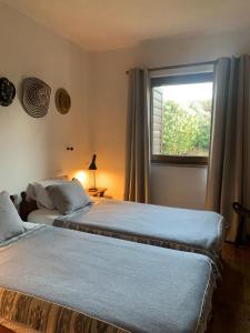 two beds in a bedroom with a window at 4Sea House in Porto Covo