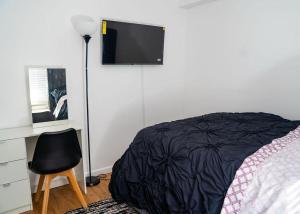a bedroom with a bed and a desk with a television at Anike's Place in Newark