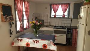a kitchen with a table with a vase of flowers on it at Pink Granite Coast Cottage between forest and sea in Trélévern