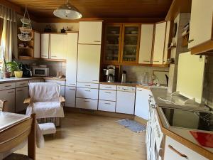 a kitchen with white cabinets and a table and a chair at Appartement zum Grenzstein in Rattersdorf +4 photos
