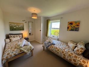 a bedroom with two beds and a window at Bruntmoor Cottage in Bakewell