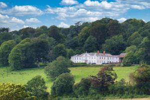 una grande casa bianca in un campo alberato di Upcott Cottage a Barnstaple