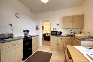 una cucina con armadi in legno e forno a piano cottura nero di Upcott Cottage a Barnstaple