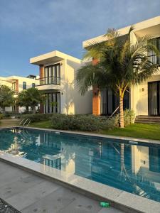 a house with a palm tree next to a swimming pool at Biệt thự nghỉ dưỡng Saint Simeon Long Hải in Ấp Phước Tĩnh