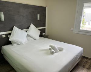 a large white bed with two towels on it at Contact Hôtel Arc-En-Ciel - Rénové in Mulhouse