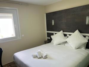 a bedroom with a white bed with two towels on it at Contact Hôtel Arc-En-Ciel - Rénové in Mulhouse