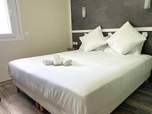a large white bed with two towels on it at Contact Hôtel Arc-En-Ciel - Rénové in Mulhouse