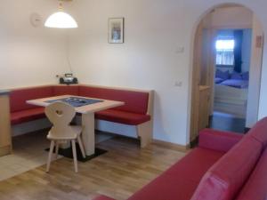 a living room with a red couch and a table at Winterklaubhof in Siusi