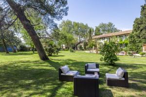 three chairs sitting in the grass under a tree at Domaine de Rhodes - 5 Chambres et 7 locations de vacances in Avignon