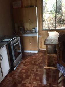 a kitchen with a stove and a wooden floor at Hermosa Cabaña Rústica Bosque Ámbar in Chillán