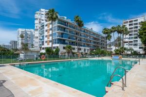ein Pool mit einem großen Apartmenthaus im Hintergrund in der Unterkunft ALAY NEARBY BEaCH in Benalmádena