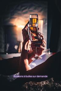 una persona che tiene in mano un bicchiere di vino di Suite craz'in Love Room, jacuzzi, cinéma, Camargue a Beaucaire