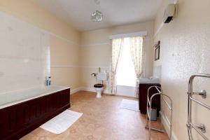 Un baño con bañera, inodoro y ventana. en Fortescue, en Barnstaple