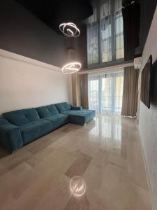 een woonkamer met een blauwe bank en ramen bij SIGMA suites in Constanţa