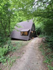a black house with a dirt road in front of it at Chalet Séquoia 138 Nature, piscine et chien bienvenu à Durbuy in Durbuy