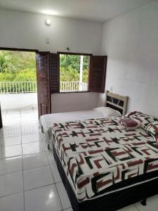 a bedroom with a bed and a large window at Tô em Casa Hospedagem 2 in Jijoca de Jericoacoara