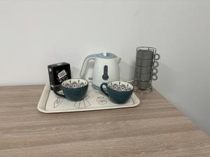 a tea kettle and two cups on a tray at Studio proche Vienne 38200 in Jardin