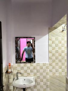 a person standing in front of a mirror in a bathroom at Sarita's homestay in Ayodhya