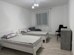 a bedroom with two beds and a desk in it at LG Apartman Siófok in Siófok
