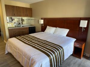 a bedroom with a large bed and a kitchen at Princess Motel in Bobcaygeon