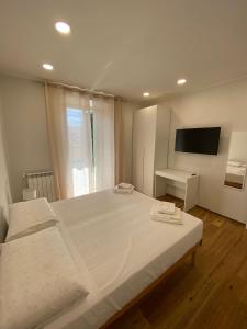a bedroom with a large white bed and a television at Begonia Apartment in Rome