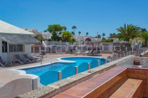 a pool at the resort with chairs and umbrellas at Bungalow Golf del Sur in San Miguel de Abona