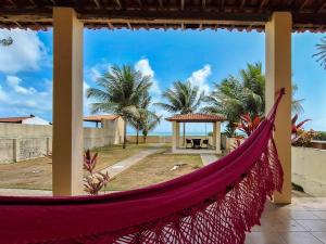 a hammock on a porch with a view of the ocean at Casa Mar Azul - Pé na areia de Praia azul in Pitimbu