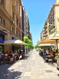 una calle con gente sentada en mesas y sombrillas en Due Passi, en Palermo