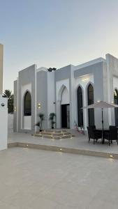 a large white building with benches and an umbrella at Lateen Chalet - شاليه لتين in Nizwa