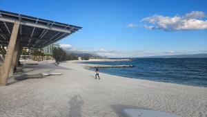 a person walking on a beach next to the water at Apartments Deja Views - Žnjan beach in Split