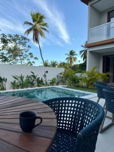a coffee cup sitting on a table next to a swimming pool at La Petite Suisse - Condomínio Charmoso em Imbassaí in Mata de Sao Joao +2 photos
