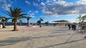 people walking on a sidewalk near the beach with palm trees at Apartments Deja Views - Žnjan beach in Split