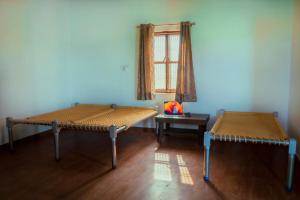 two beds in a room with a table and a window at Chaudhary Farm house in Daula +39 photos
