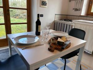 a white table with a bottle of wine and cheese at Podere Diacciolini near Massa Marittima in Fontalcinaldo +17 photos