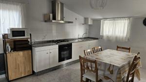 a kitchen with a table and a stove and a microwave at Area Pequena ATICO in Malpica
