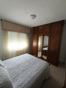 a bedroom with a bed and a large wooden cabinet at Casa O Con in O Grove