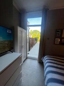 a bedroom with a bed and a television and a window at Wimbledon fortnight in London